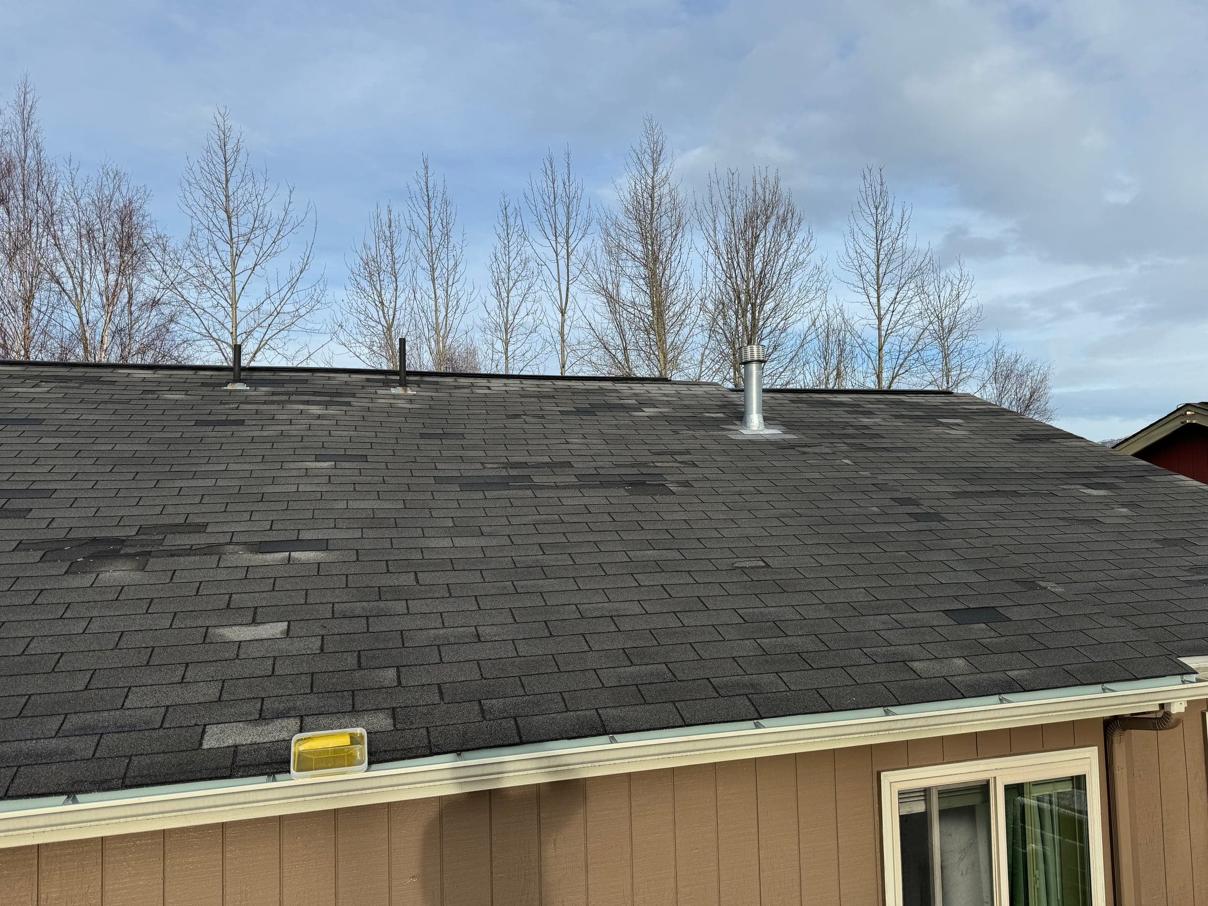 Anchorage roof showing wind damage with missing shingle tabs requiring repair